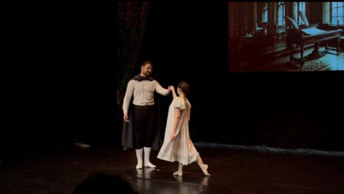 Tanzpaar auf der Bühne, einer in einem eleganten Kostüm, die andere in einem weißen Kleid.