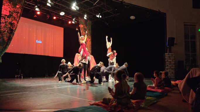 Zirkusaufführung mit Akrobaten und tanzenden Darstellern auf der Bühne.