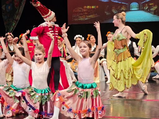 Tanzende Kinder in bunten Kostümen bei einer Aufführung auf der Bühne.