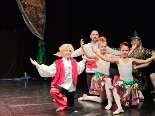 Kinder in traditioneller Tracht führen einen Tanz auf einer Bühne auf.