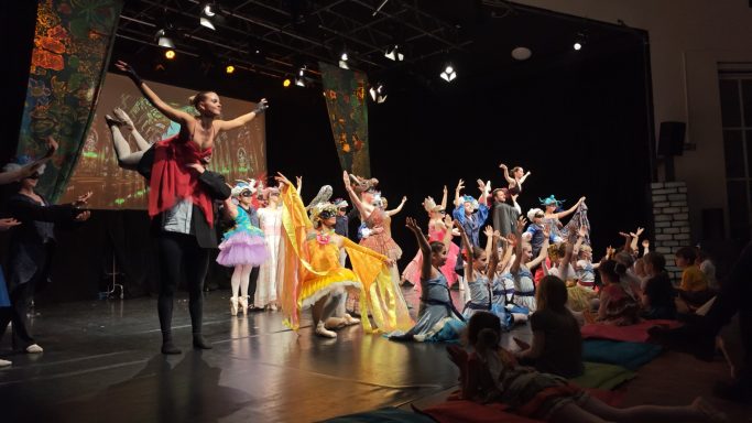 Bunte Theaterszene mit Schauspielern in farbenfrohen Kostümen auf der Bühne.